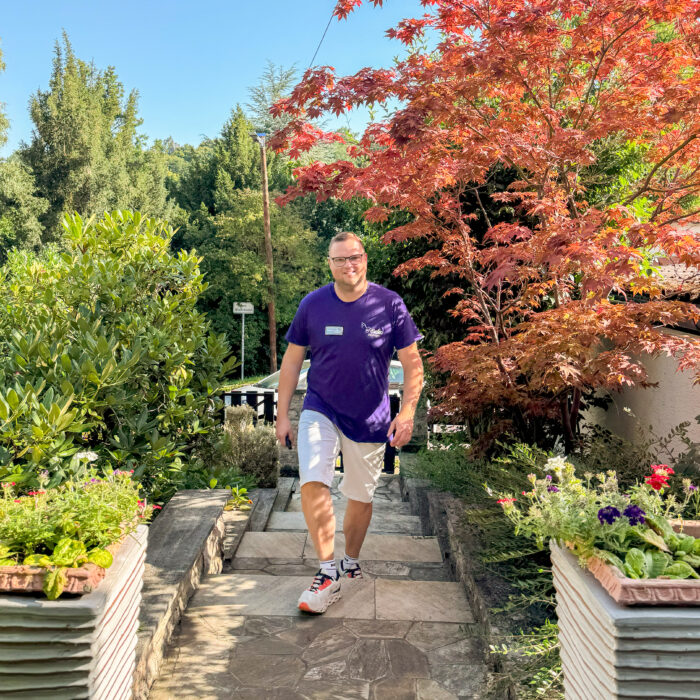 Lächelnder Pflegedienstmitarbeiter geht Treppe eines Vorgartens in Eisenach hinauf